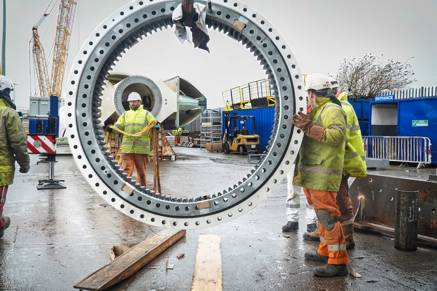 Construction Workers Handling Large Gear